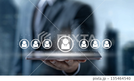 Businessman holding a tablet with digital people icons, symbolizing HR management, recruitment, and talent selection in a modern corporate environment 135464540