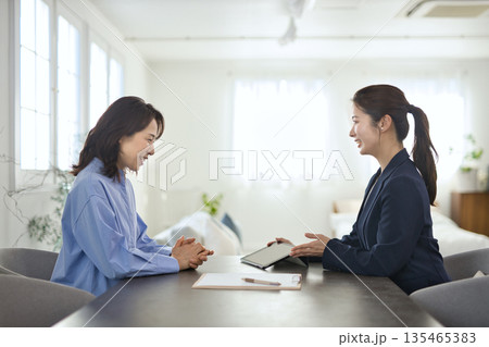 ミドル女性に説明をする若いビジネスウーマン ミドル女性に説明をする若いビジネスウーマン 135465383