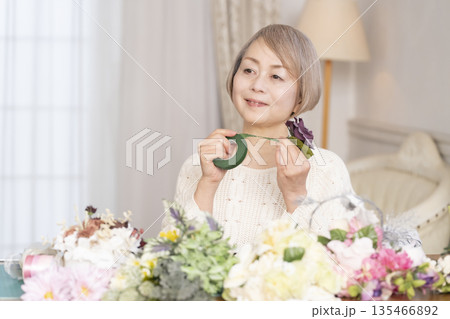 リビングで趣味のフラワーアレンジメントをするシニア女性 リビングで趣味のフラワーアレンジメントをするシニア女性 135466892