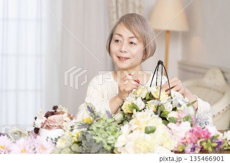 リビングで趣味のフラワーアレンジメントをするシニア女性 リビングで趣味のフラワーアレンジメントをするシニア女性 135466901