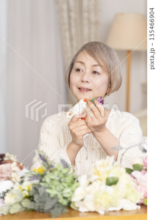 リビングで趣味のフラワーアレンジメントをするシニア女性 リビングで趣味のフラワーアレンジメントをするシニア女性 135466904