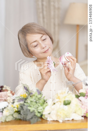 リビングで趣味のフラワーアレンジメントをするシニア女性 リビングで趣味のフラワーアレンジメントをするシニア女性 135466908