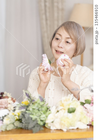 リビングで趣味のフラワーアレンジメントをするシニア女性 135466910