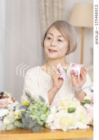 リビングで趣味のフラワーアレンジメントをするシニア女性 135466913