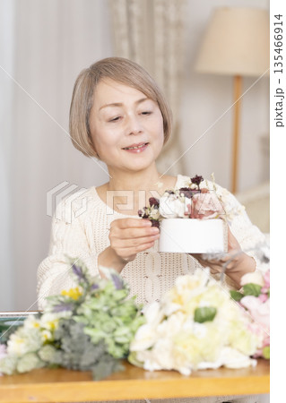 リビングで趣味のフラワーアレンジメントをするシニア女性 135466914