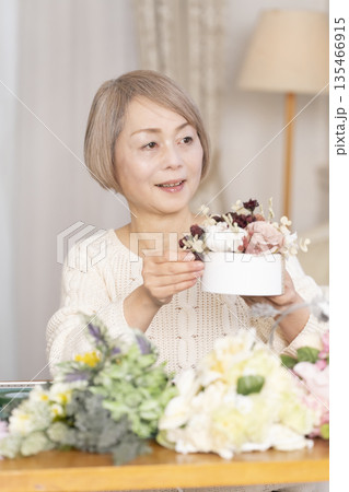 リビングで趣味のフラワーアレンジメントをするシニア女性 135466915