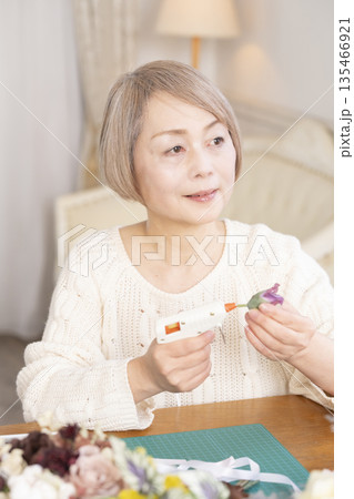 リビングで趣味のフラワーアレンジメントをするシニア女性 135466921