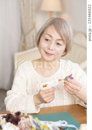 リビングで趣味のフラワーアレンジメントをするシニア女性 リビングで趣味のフラワーアレンジメントをするシニア女性 135466922