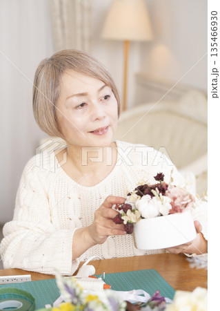 リビングで趣味のフラワーアレンジメントをするシニア女性 135466930
