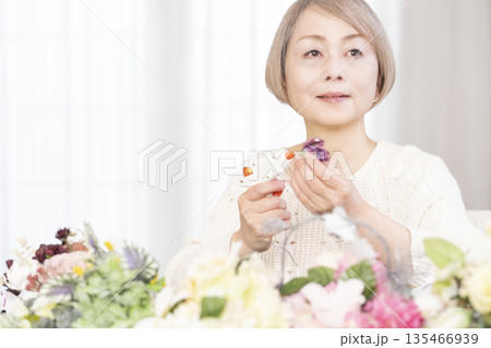 リビングで趣味のフラワーアレンジメントをするシニア女性 135466939