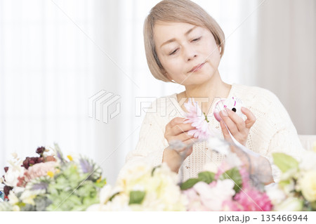 リビングで趣味のフラワーアレンジメントをするシニア女性 135466944