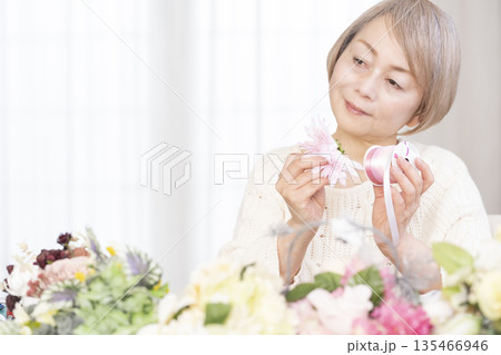 リビングで趣味のフラワーアレンジメントをするシニア女性 135466946