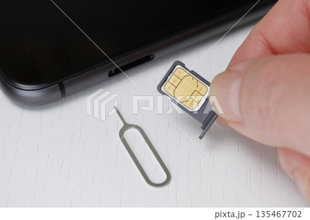 スマートフォンにSIMをセットする右手 スマートフォンにSIMをセットする右手 135467702