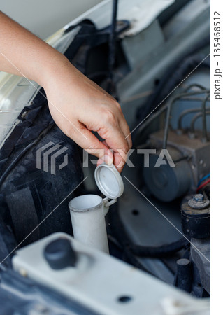 Close up of a hand of woman is checking a liquid coolant pot Close up of a hand of woman is checking a liquid coolant pot 135468512