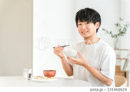 食卓でお米,白米を食べる若いアジア人男性（価格高騰,物価高,物価上昇） 135468629