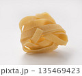 Italian dry fettuccine or tagliatelle pasta over white background with shadow 135469423