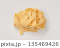 Italian dry fettuccine or tagliatelle pasta over white background with shadow top view 135469426