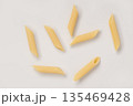 Italian dry penne rigate pasta over white background with shadow top view 135469428