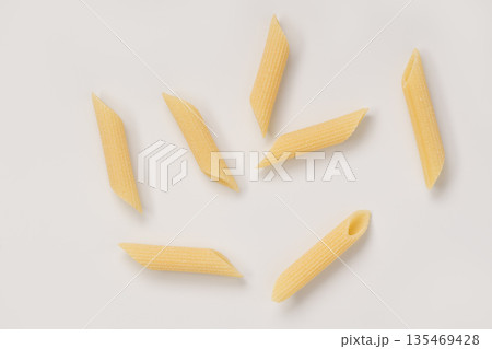 Italian dry penne rigate pasta over white background with shadow top view Italian dry penne rigate pasta over white background with shadow top view 135469428