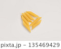 Italian dry penne rigate pasta over white background with shadow top view 135469429