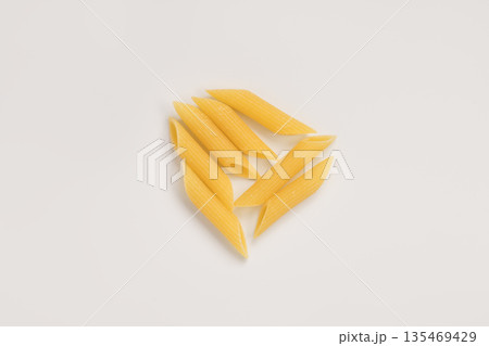 Italian dry penne rigate pasta over white background with shadow top view 135469429