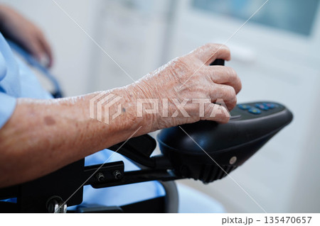 Asian elderly disability woman patient use joystick electric wheelchair in hospital. 135470657