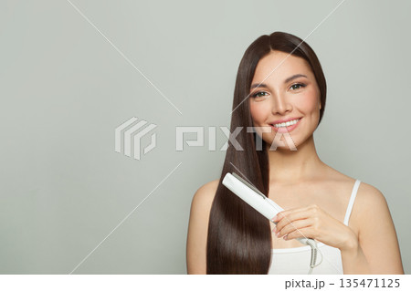 Pretty woman brunette with long straight smooth hairstyle using hair straightener iron Pretty woman brunette with long straight smooth hairstyle using hair straightener iron 135471125