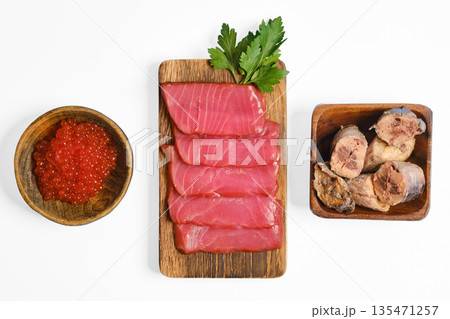 Freshly sliced fish with fish roe and preserved fish on a wooden platter in a clean kitchen setting Freshly sliced fish with fish roe and preserved fish on a wooden platter in a clean kitchen setting 135471257