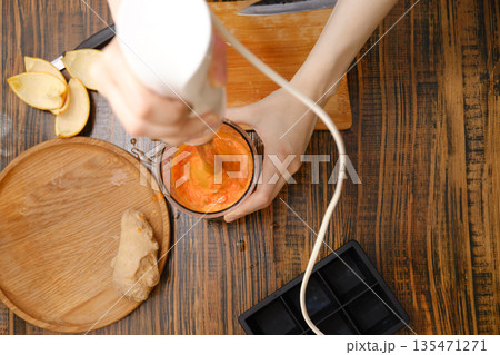 Preparing a smoothie with fruits and ginger in a kitchen setting during the day Preparing a smoothie with fruits and ginger in a kitchen setting during the day 135471271