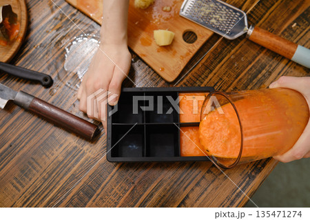 Preparing a vegetable mixture in the kitchen for storage in a container on a wooden table Preparing a vegetable mixture in the kitchen for storage in a container on a wooden table 135471274