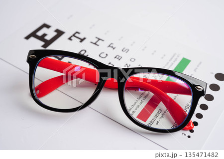 Glasses on eye testing exam chart to check eyesight accuracy of reading. Glasses on eye testing exam chart to check eyesight accuracy of reading. 135471482