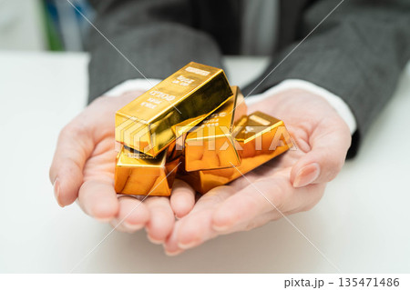 Asian woman holding gold bar in finance business. Asian woman holding gold bar in finance business. 135471486