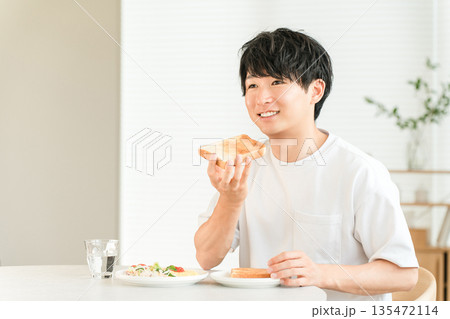 朝食に食パンのトーストとサラダを食べる若いアジア人男性 朝食に食パンのトーストとサラダを食べる若いアジア人男性 135472114