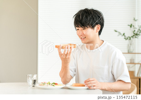 朝食に食パンのトーストとサラダを食べる若いアジア人男性 朝食に食パンのトーストとサラダを食べる若いアジア人男性 135472115