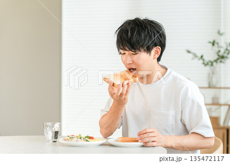 朝食に食パンのトーストとサラダを食べる若いアジア人男性 135472117
