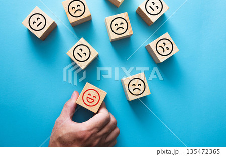 Hand picking happy smiley block for customer feedback concept 135472365