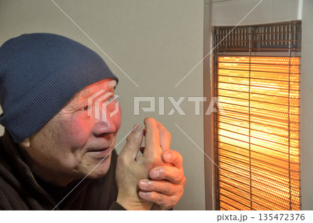 電気ストーブで暖をとる老人 135472376