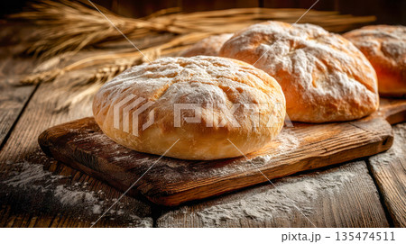 Freshly baked rustic round bread on a wooden board, dusted with flour, traditional artisan baking and homemade bread concept 135474511