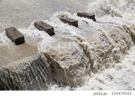 Concrete blocks in flowing water, turbulent river scene Concrete blocks in flowing water, turbulent river scene 135474583