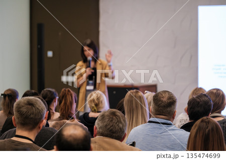 Speaker presents at conference to attentive audience in modern meeting room with projector Speaker presents at conference to attentive audience in modern meeting room with projector 135474699
