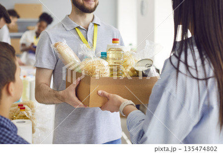 Close Up Of Volunteer Hands Passing Food Box To Refugee 135474802