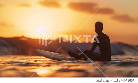 夕焼けの海に浮かぶサーファーのシルエットと静かなゴールデンアワー 135474904