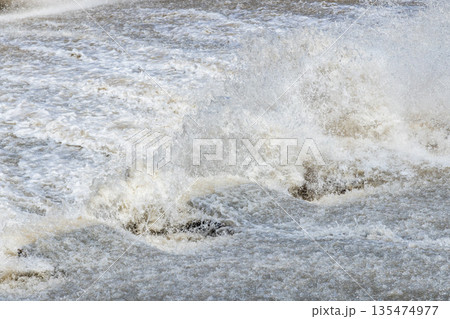 Turbulent water splashing in a river during daytime 135474977