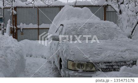 A grey car, partially cleared of fallen snow in a private yard under a light coating of frost, parked among deep snowdrifts following abnormal weather conditions A grey car, partially cleared of fallen snow in a private yard under a light coating of frost, parked among deep snowdrifts following abnormal weather conditions 135475176