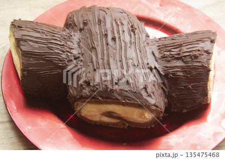 chocolate yule log dessert on red plate 135475468