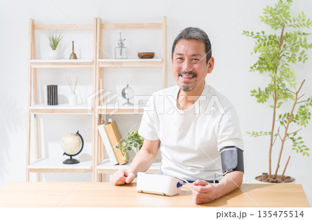 血圧計で血圧を測定する中高年男性 135475514