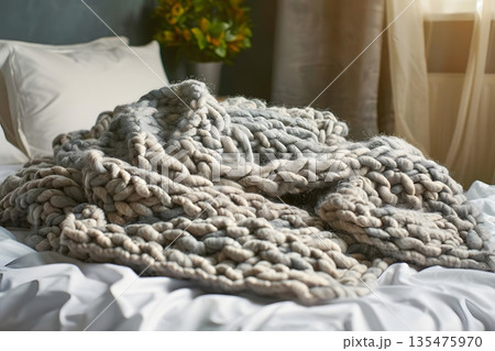 ベッドに無造作に置かれたニットブランケットの温もりある寝室 135475970