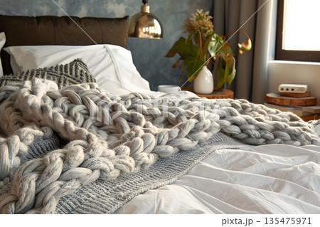 ベッドに無造作に置かれたニットブランケットの温もりある寝室 ベッドに無造作に置かれたニットブランケットの温もりある寝室 135475971