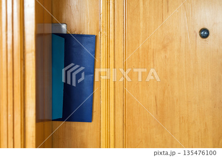 Envelope with a letter inserted through the hotel room door slot, welcoming guests with a warm message hospitality comfort during their stay Envelope with a letter inserted through the hotel room door slot, welcoming guests with a warm message hospitality comfort during their stay 135476100