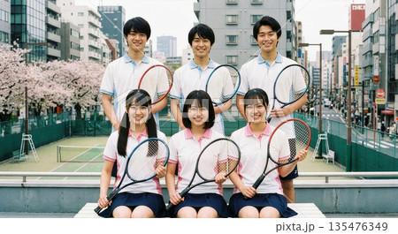 満開の桜とビル街を背景に集まるテニスサークルの男女メンバー 135476349